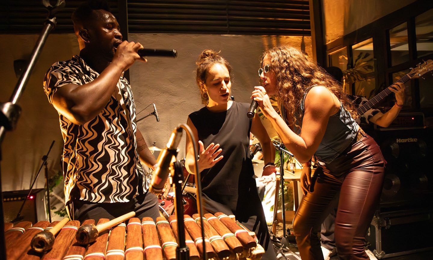 Yadi Camara y dos vocalistas cantan frente a un balafón durante una actuación.