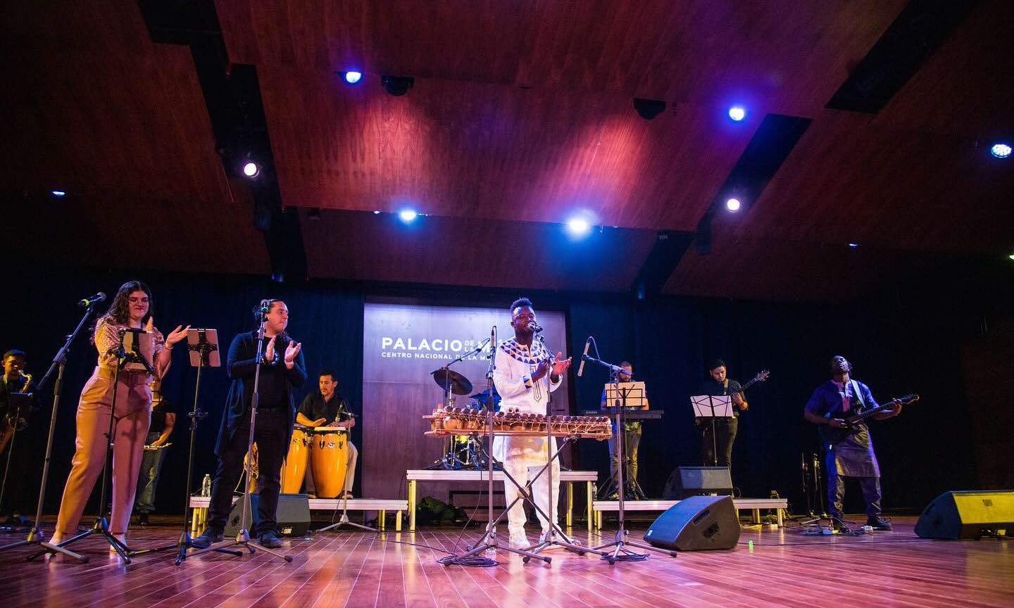 Yadi Camara frente al balafón durante una presentación con músicos y vocalistas.