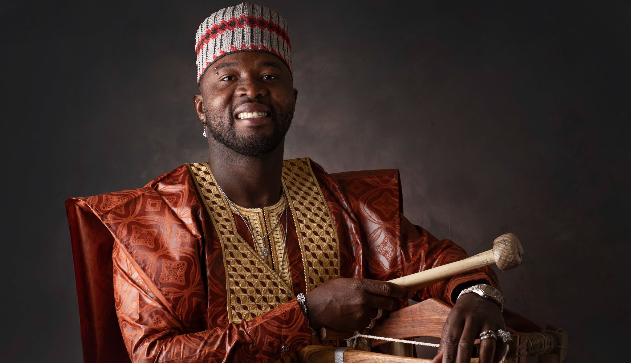 Yadi Camara sonríe con baquetas frente al balafón.